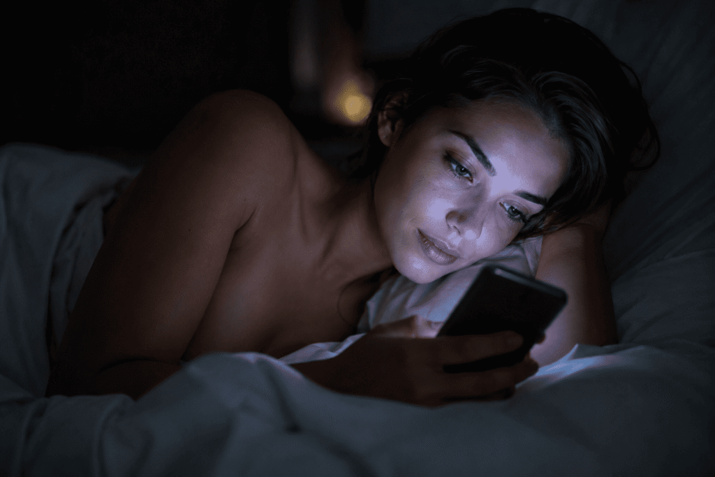 Générateur d'image ia sans censure gratuit mockup femme lit nuit smartphone éclairage visage.