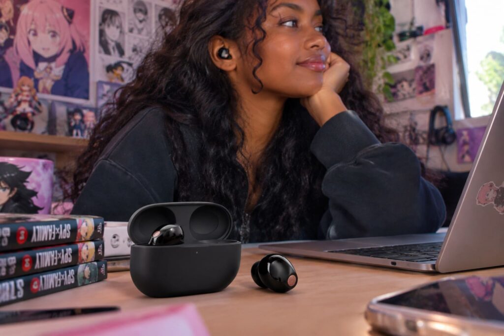 Les écouteurs Sony WF-1000XM5 posé sur une table à côté d'un ordinateur portable